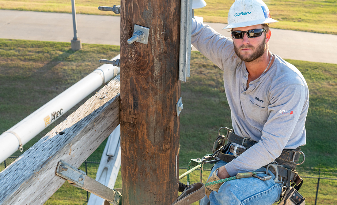 Jeshua Price (JP), lineman works on a power line while climbing a pole.